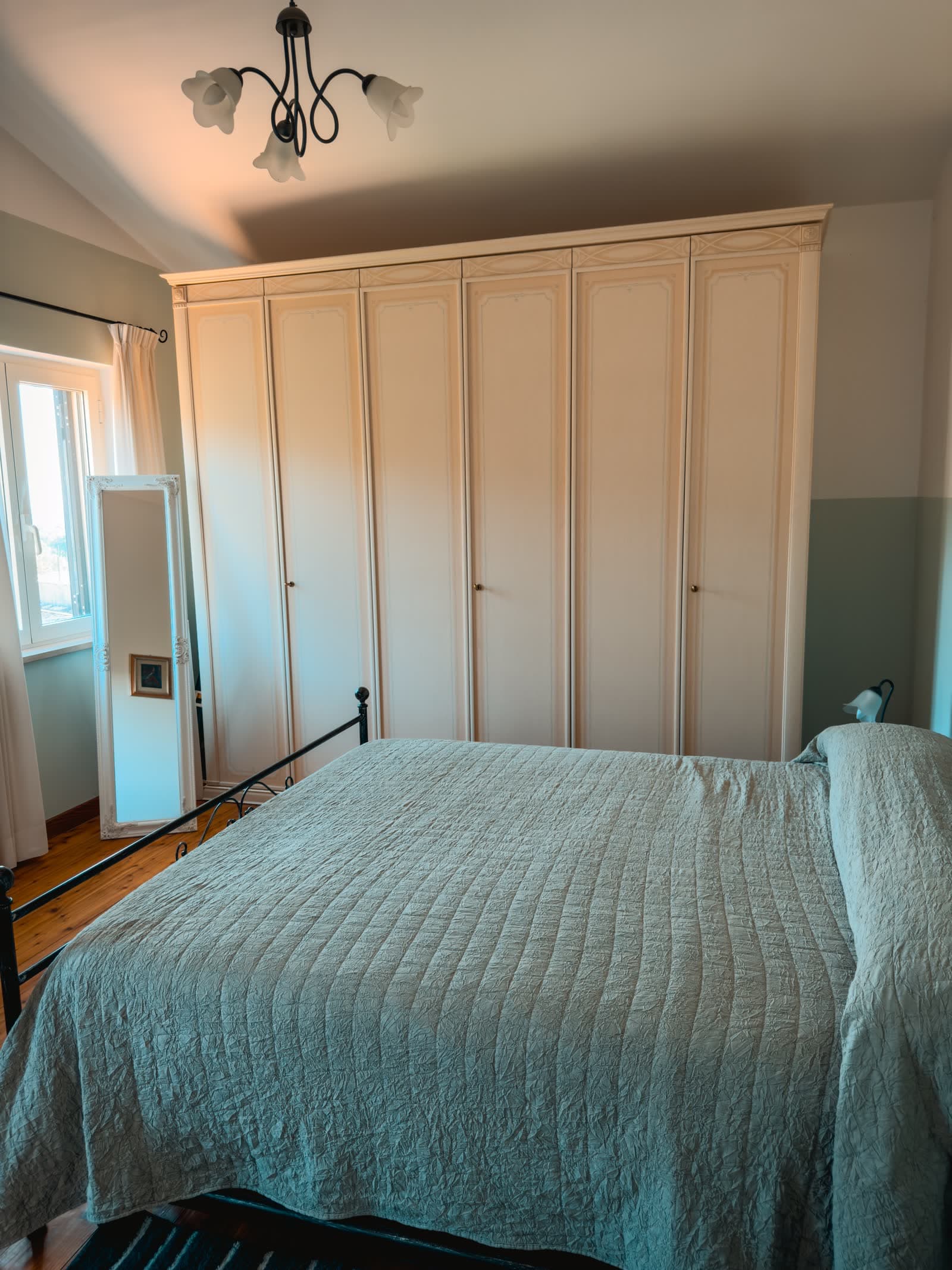 Bedroom with a large cream wardrobe and a standing mirror