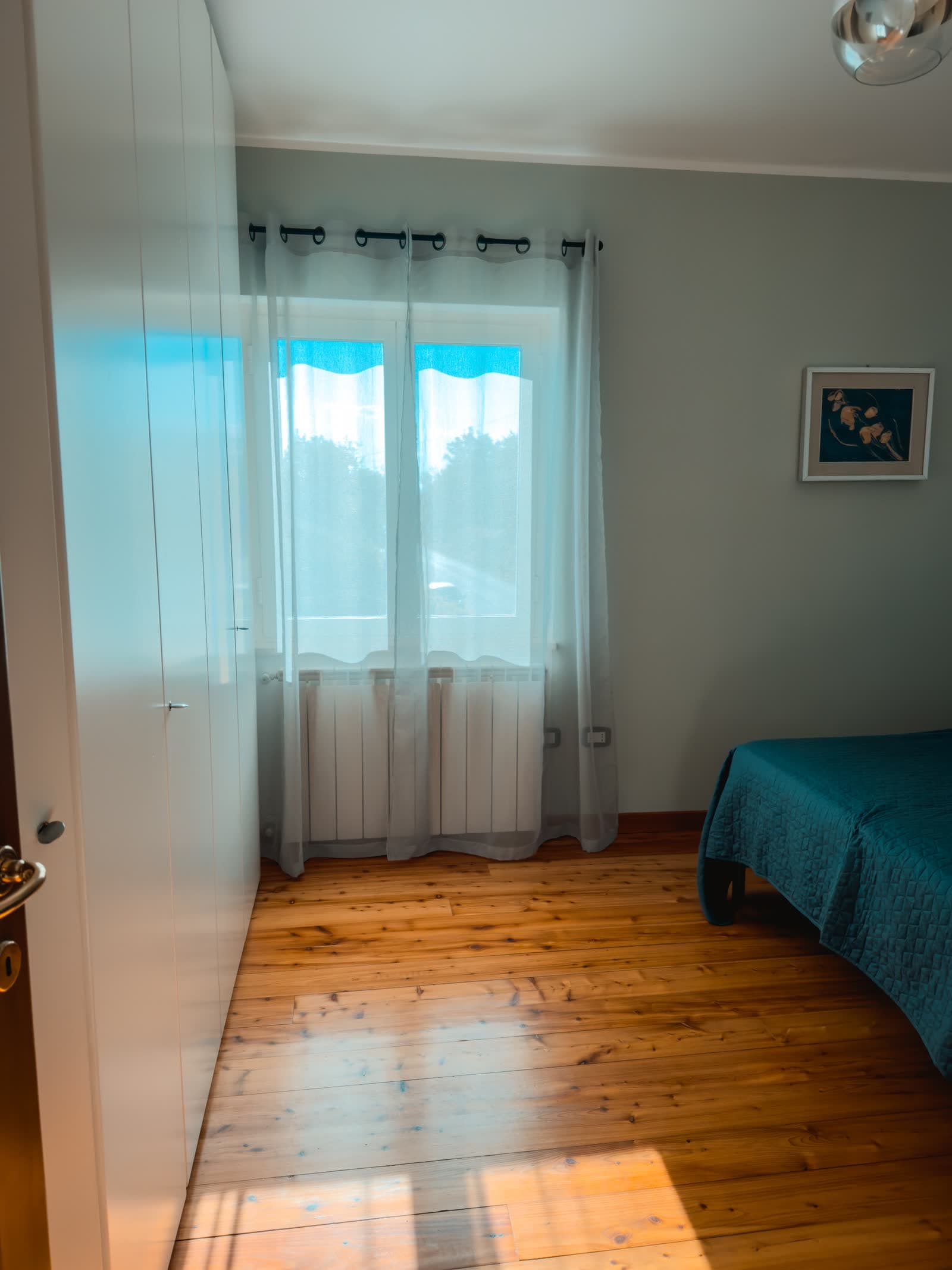 A corner of the bedroom, with wardrobe and a window onto the garden