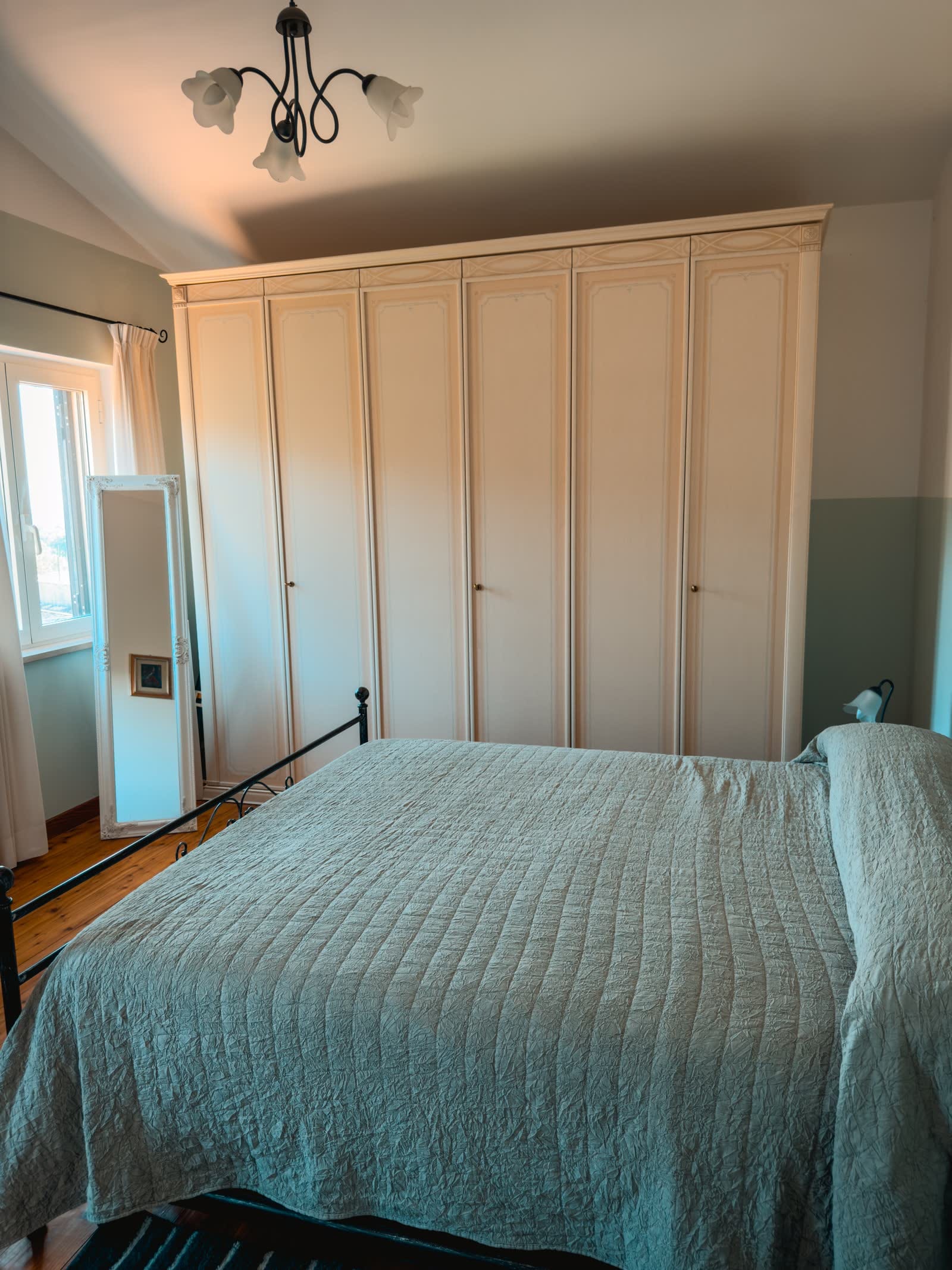 Bedroom with a large cream wardrobe and a standing mirror
